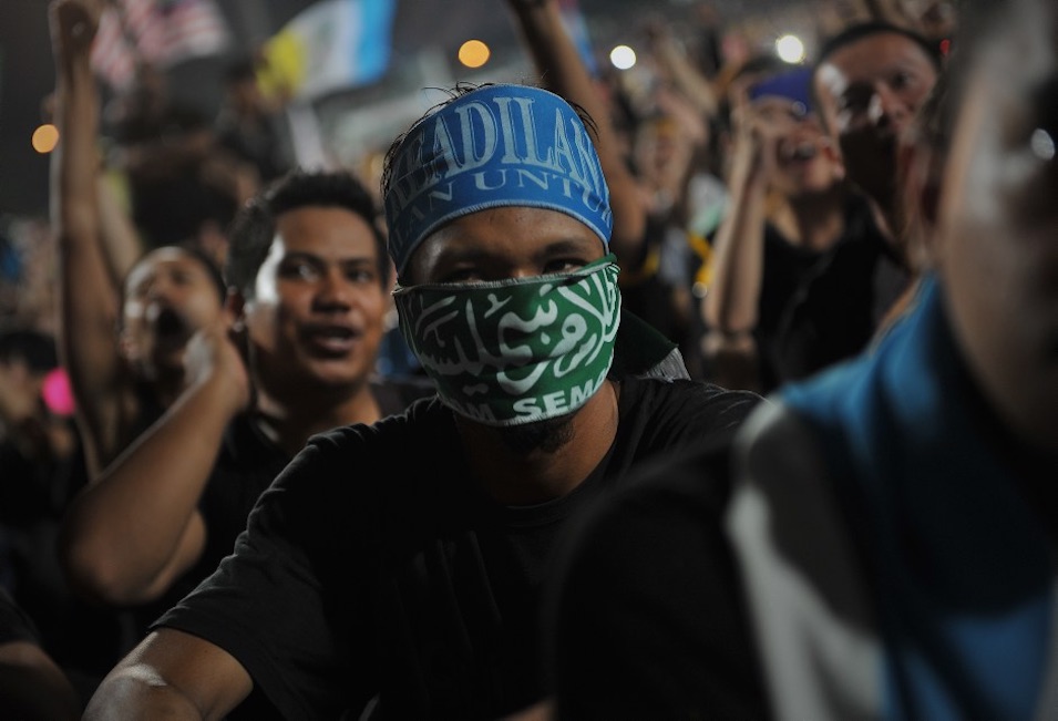 The original Wikipedia Commons caption reads (more or less): "Thousands of Malaysians dressed in mourning black gathered in Kuala Lumpur on May 8, 2013 to denounce national elections that they claim were stolen through fraud by the coalition that has ruled for 56 years." Firdaus Latif is the photographer.