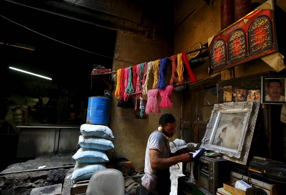 Hisham Aly, 37, takes an order on the phone at a dye workshop in old Cairo, Egypt, March 17, 2016. Egypt's hard currency crisis and competition from modern factories in Asia and at home threaten one of the last dye workshops in Egypt. But one of its owners takes comfort in the trade's ancient resilience. Mohamed Mostafa boasts that the profession dates back 3,000 years, so it can survive anything. REUTERS/Amr Abdallah Dalsh SEARCH "AMR DYE" FOR THIS STORY. SEARCH "THE WIDER IMAGE" FOR ALL STORIES