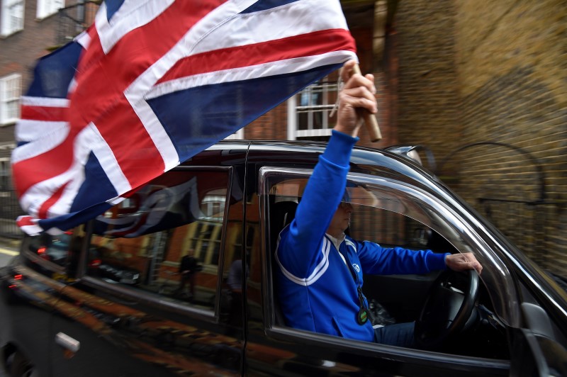 A taxi driver holds a Union flag, as he celebrates following the result of the EU referendum, in central London, Britain June 24, 2016. REUTERS/Toby Melville